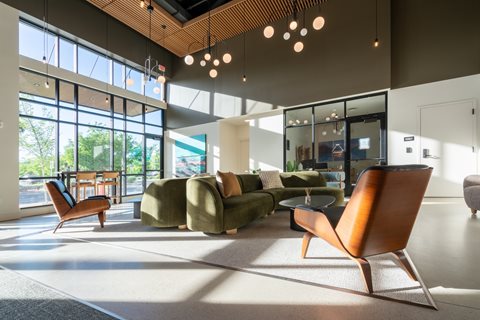 A modern living room with a large window and a variety of seating options.