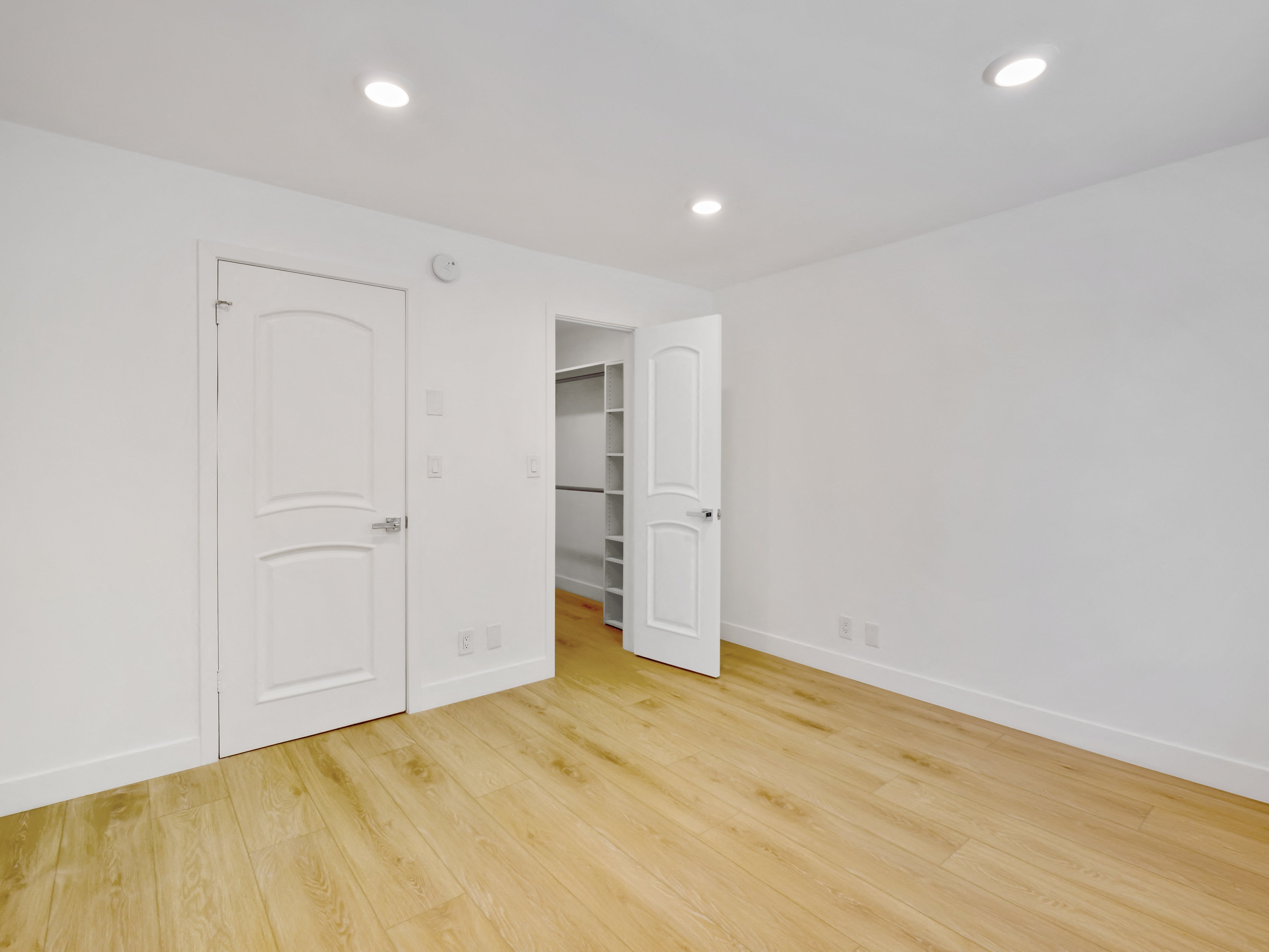 a bedroom with white walls and hardwood floors
