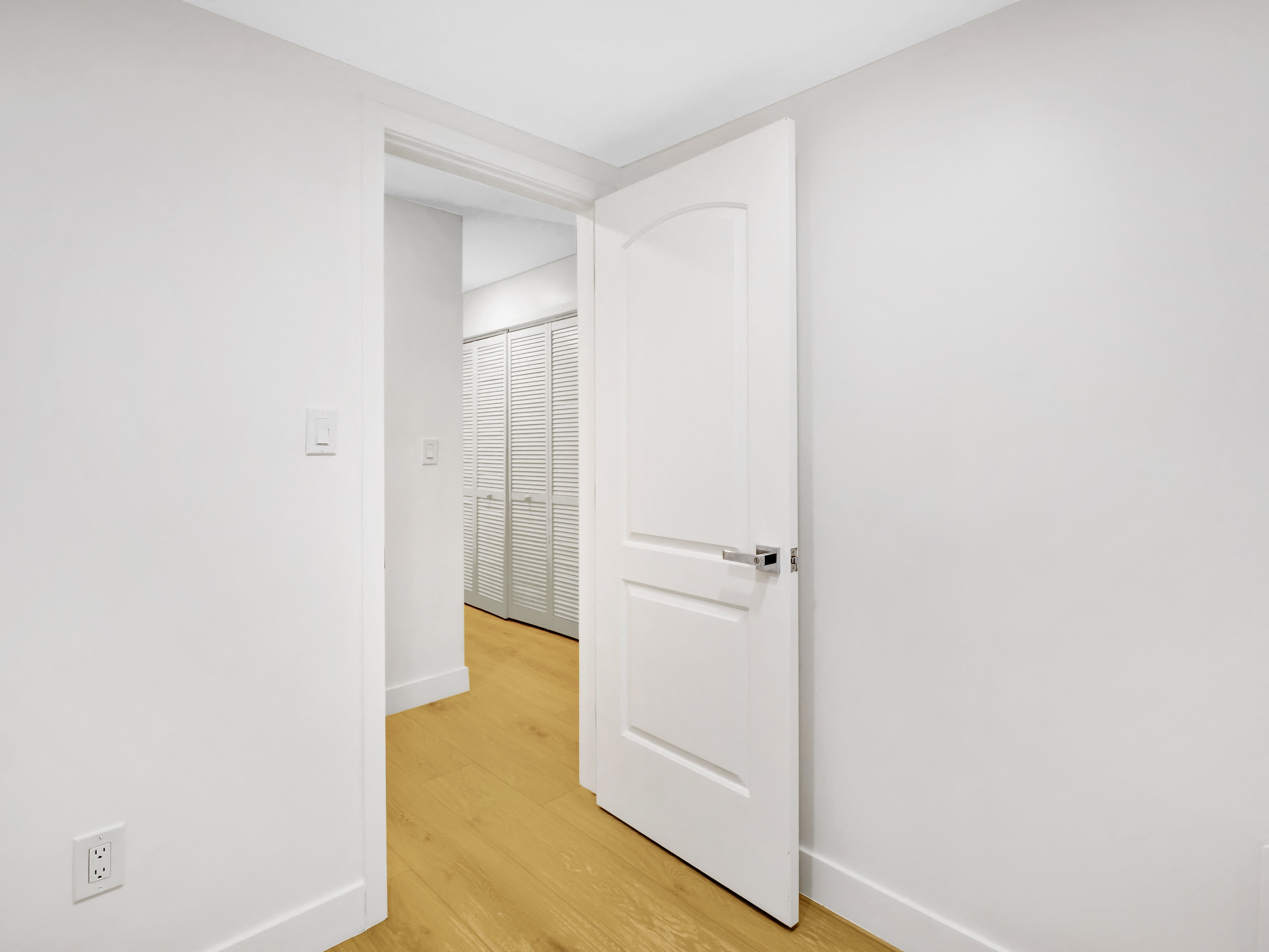 a bedroom with white walls and hardwood floors