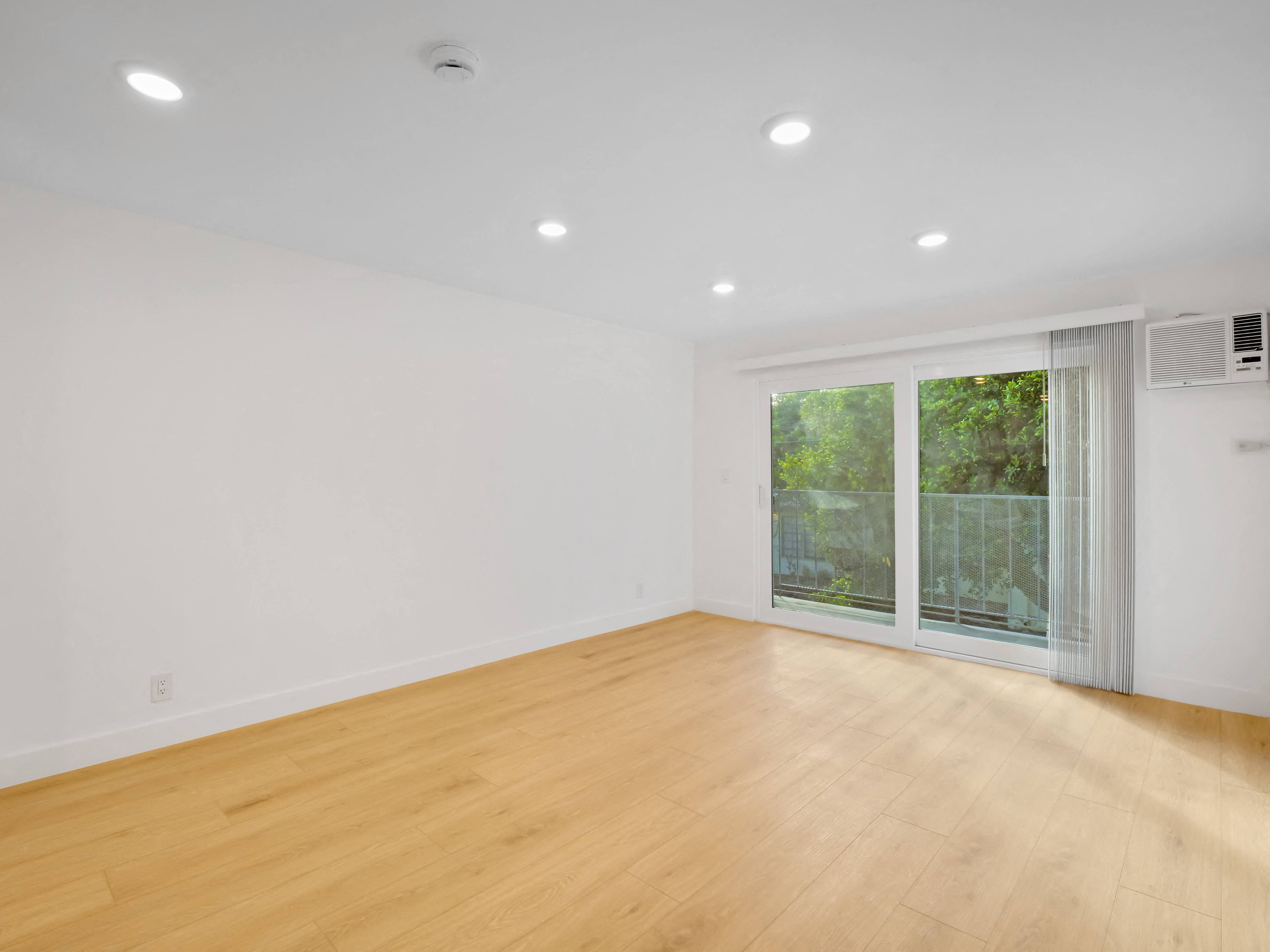 a bedroom with a sliding glass door and hardwood floors