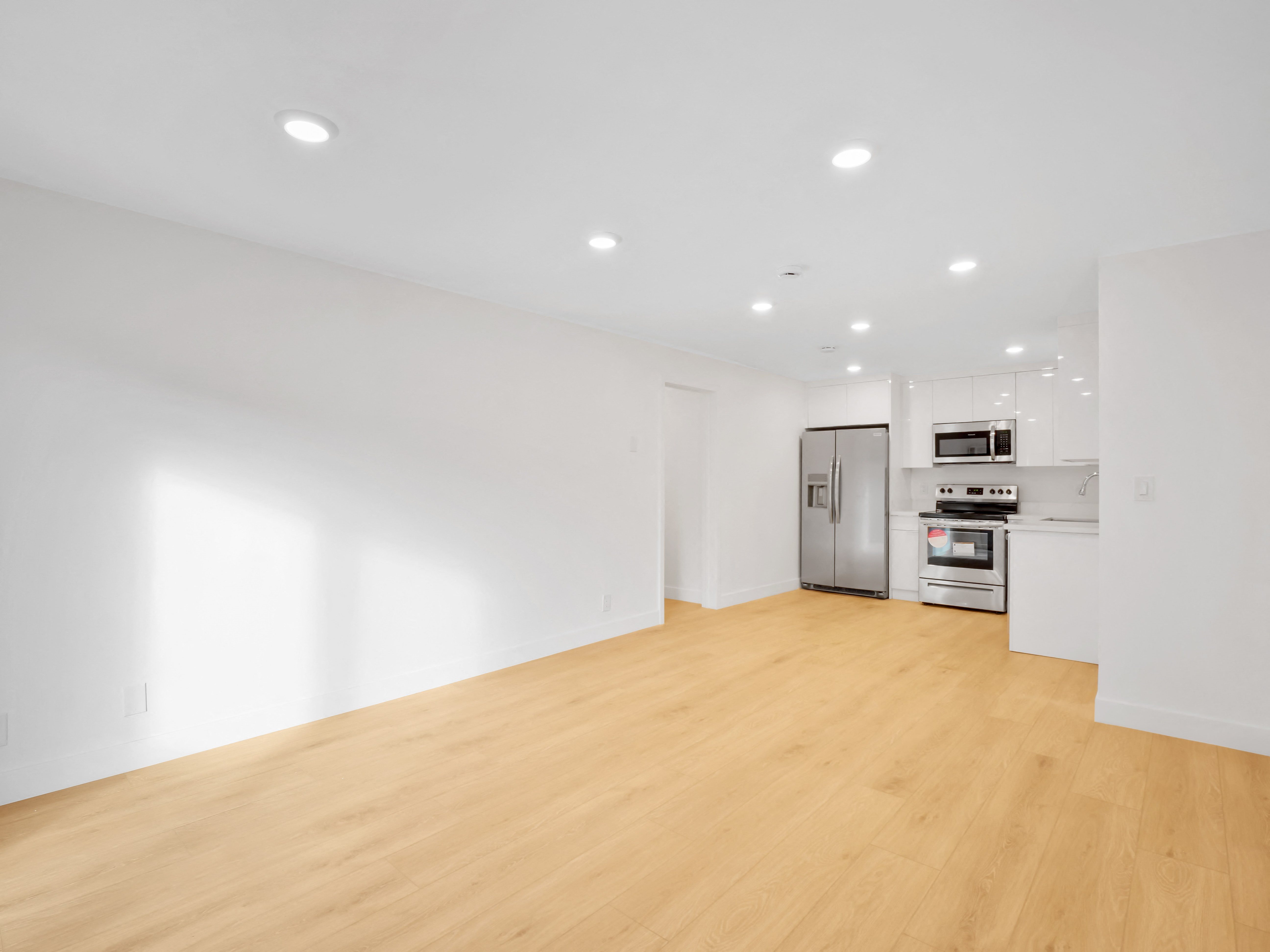 a bedroom with a medium sized bed and a kitchen with stainless steel appliances