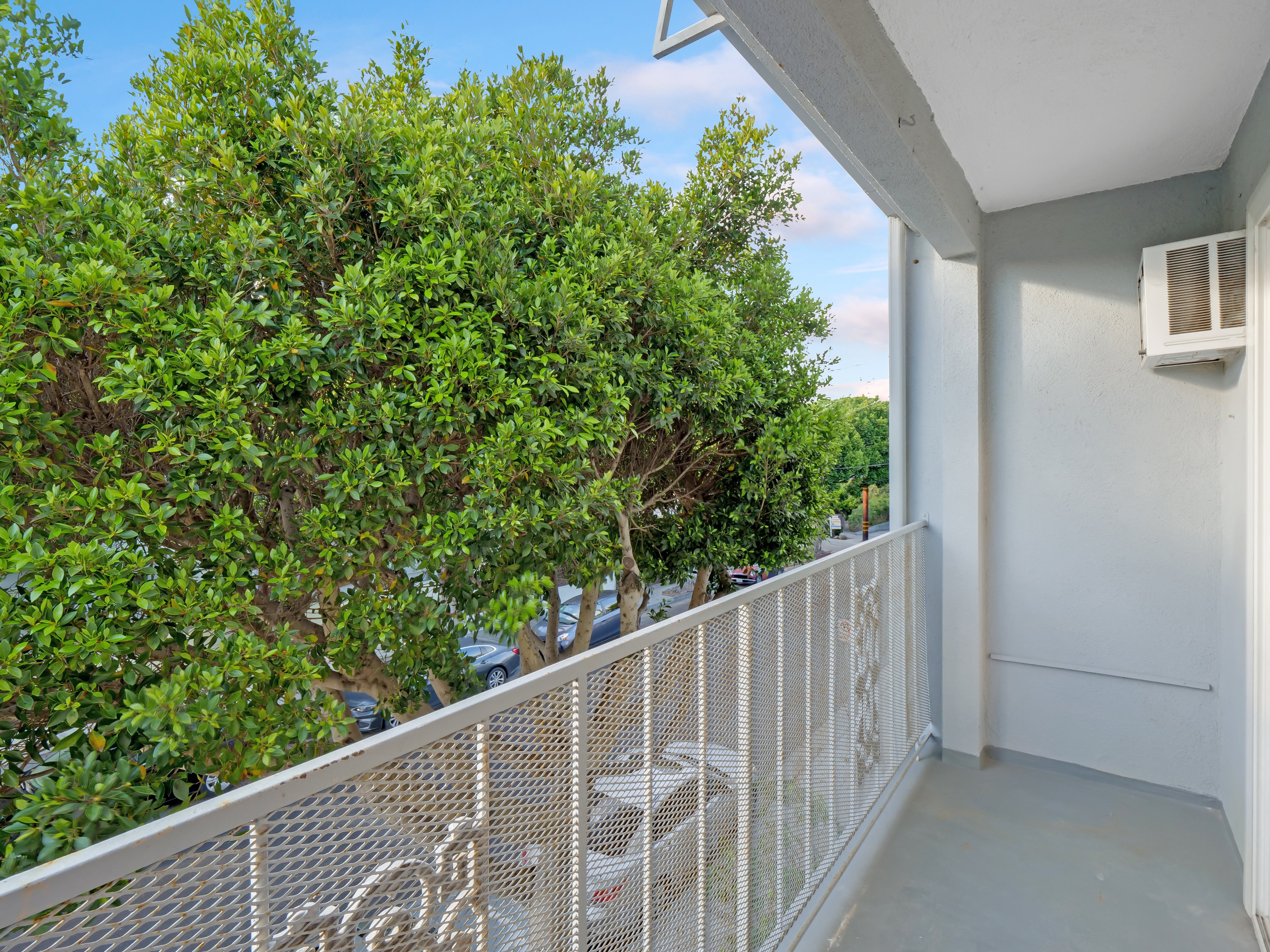 a balcony with a white railing and trees in the background