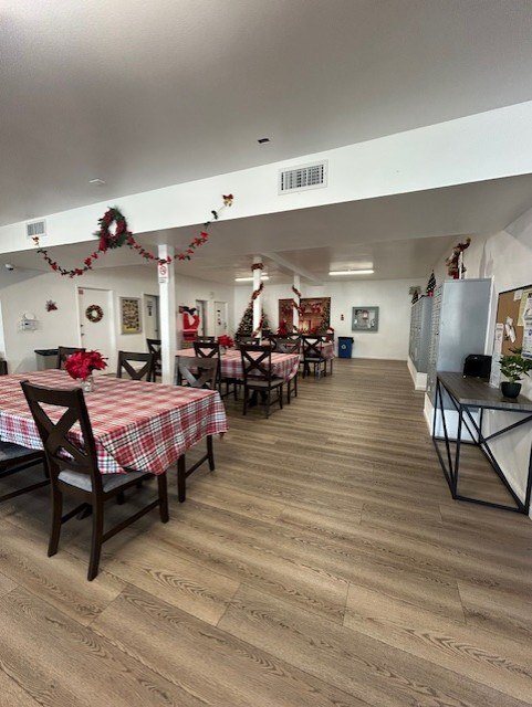 A room with wooden floors and tables set for a meal.