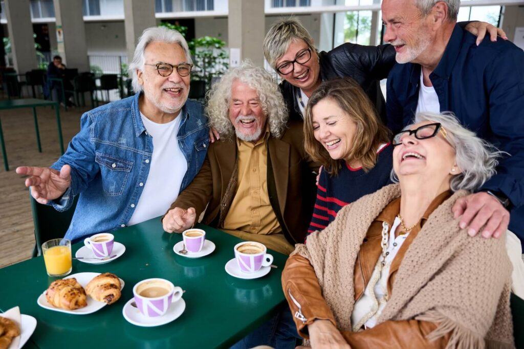 A group of people are gathered around a table with food and drinks.
