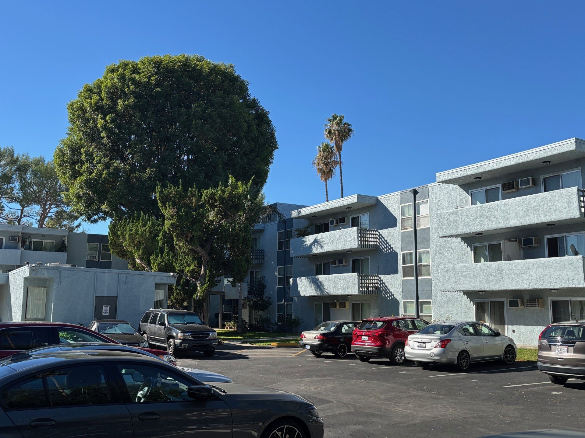 A parking lot with cars and apartment buildings in the background.