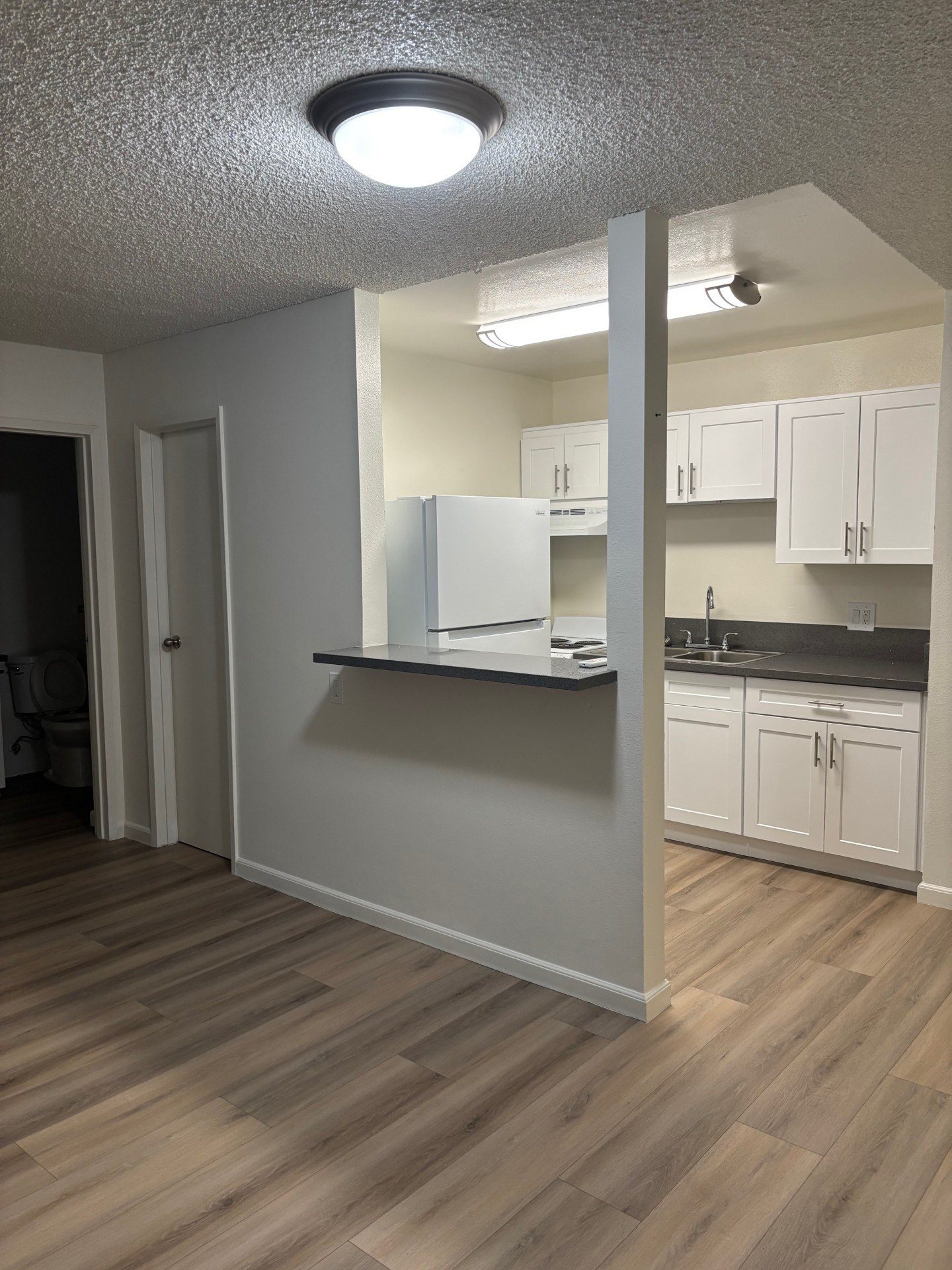 A kitchen with white cabinets and a refrigerator.