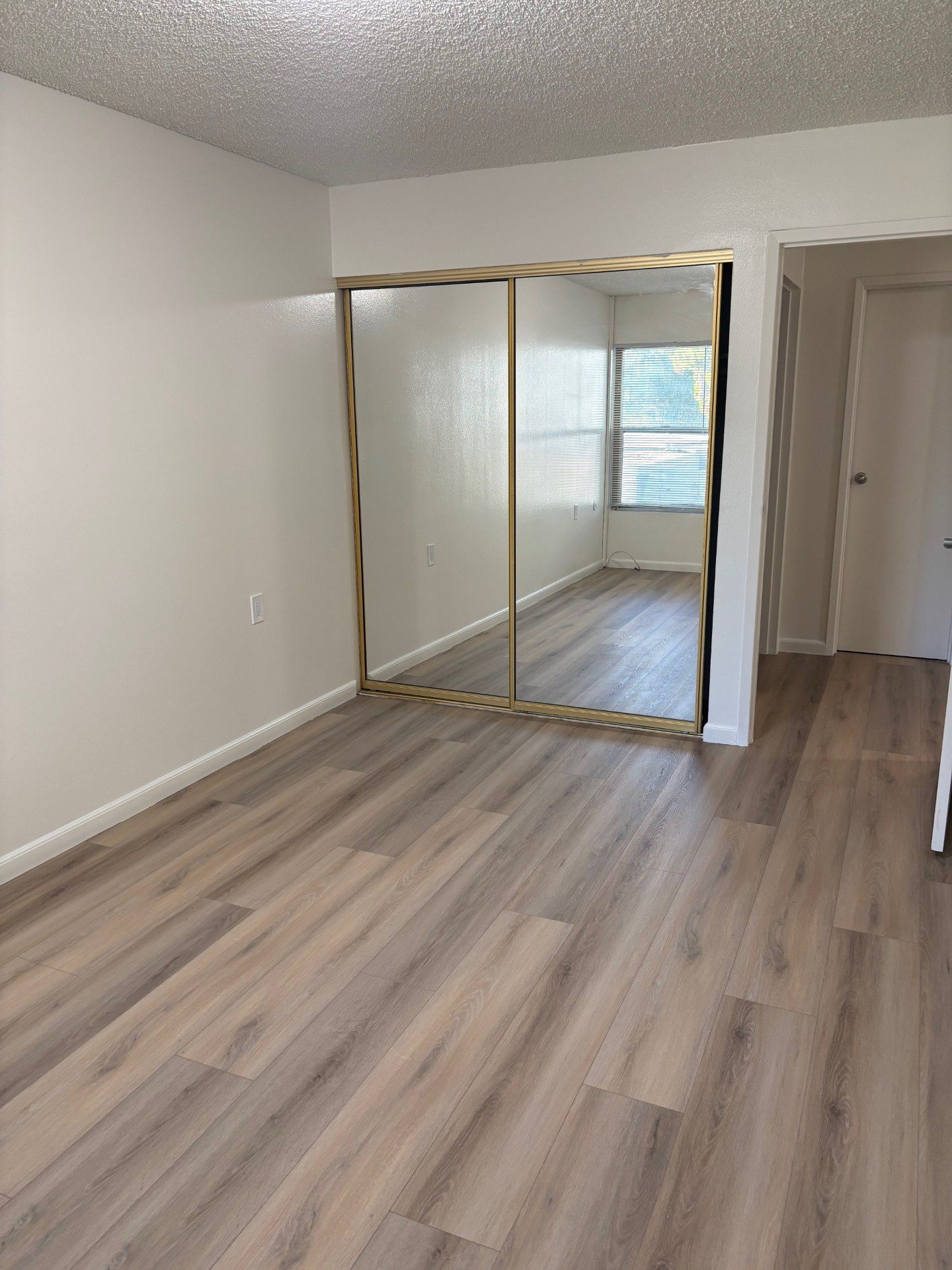 A room with a wooden floor and a large mirror on the wall.