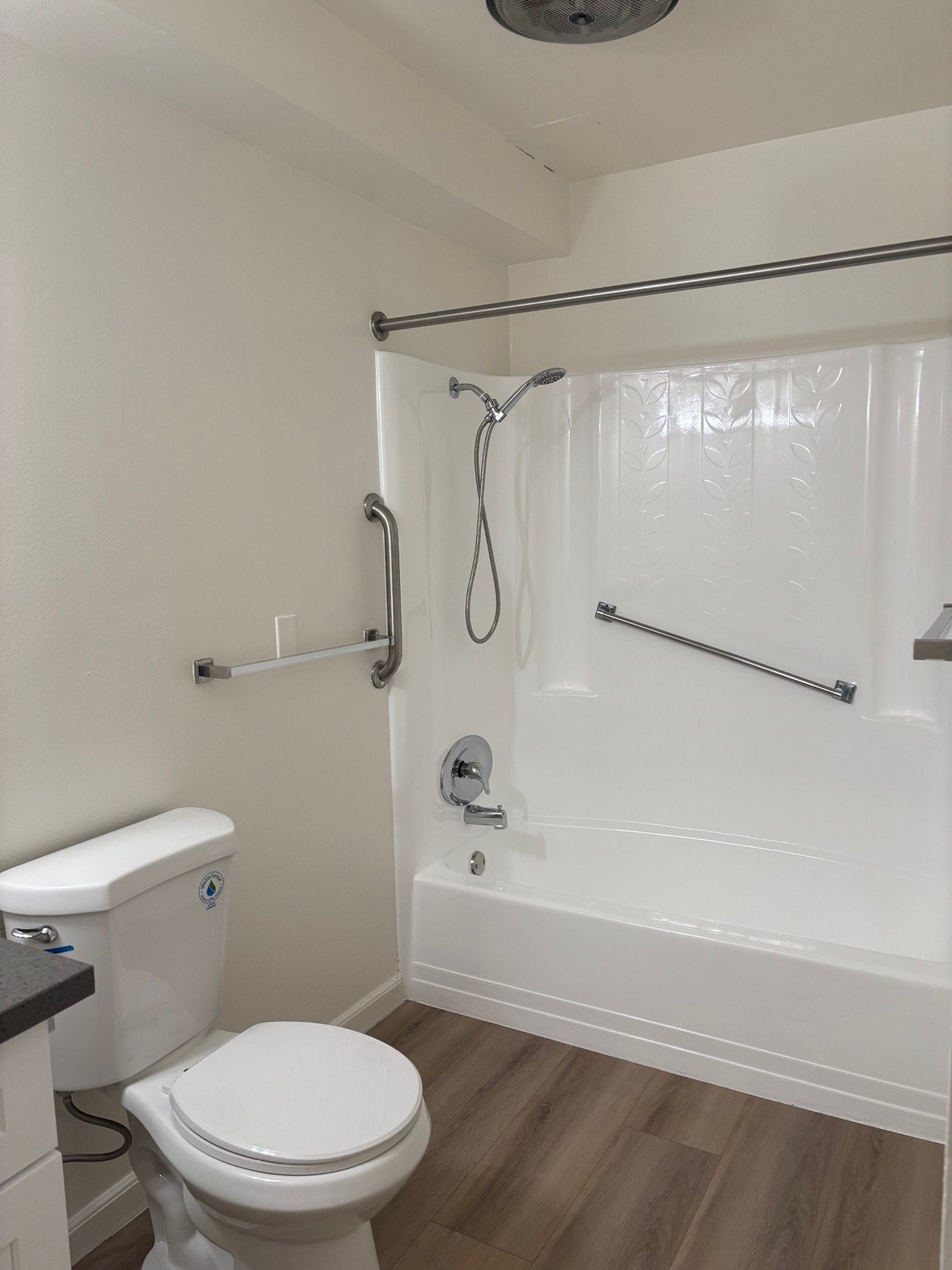 A white toilet sits next to a white bathtub in a bathroom.
