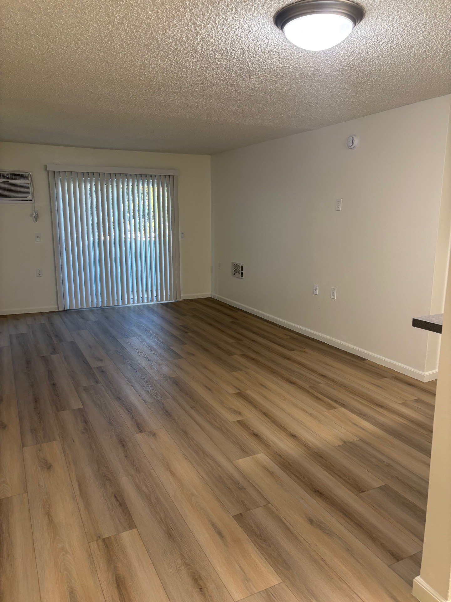 A room with wooden flooring and a window with blinds.