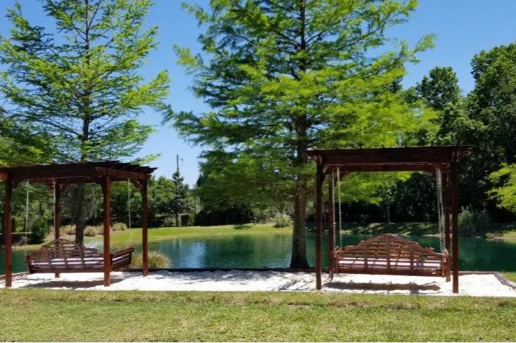 2 Pergola swing beds located on top of sand box located near the pond.