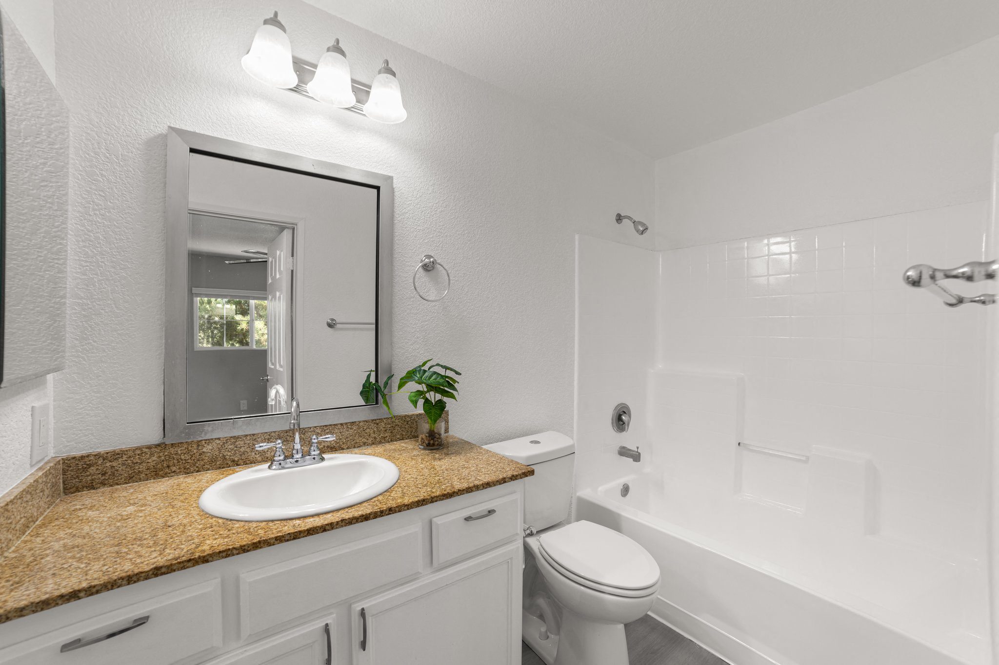 A bathroom with a sink, mirror, toilet and bathtub.