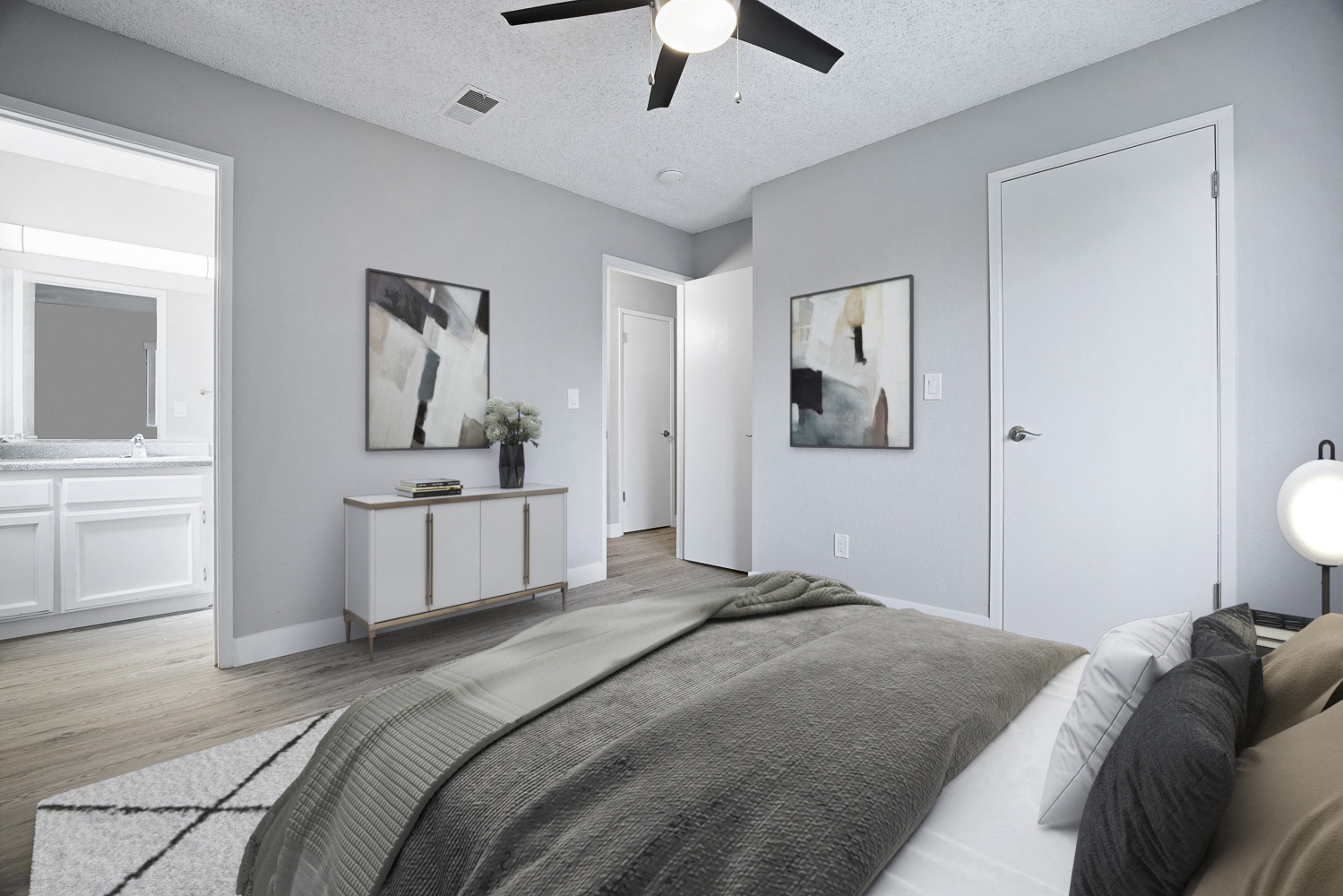 A bedroom with a bed, a ceiling fan, and two framed pictures on the wall.
