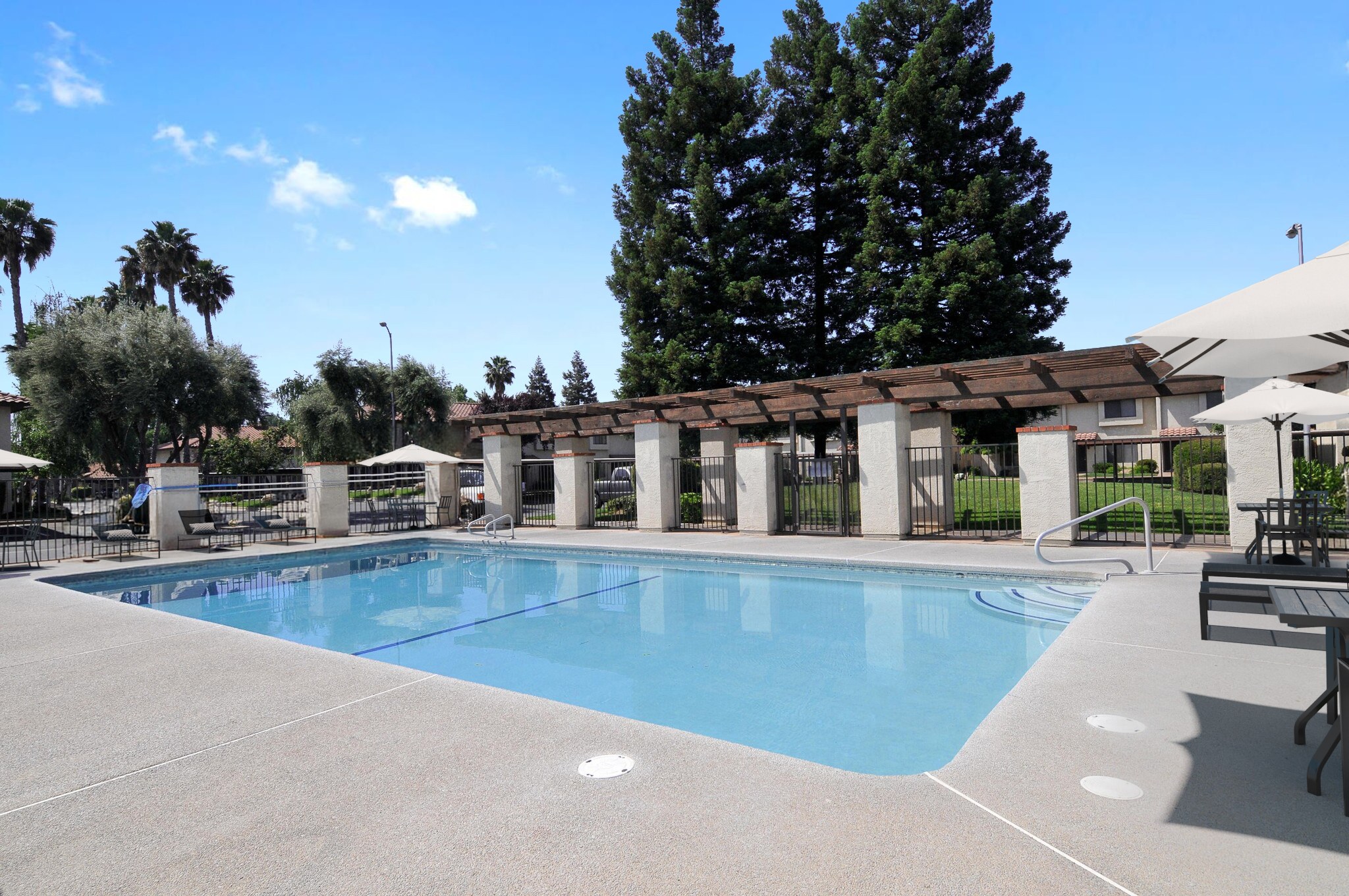 A large swimming pool surrounded by a concrete patio and a covered walkway.
