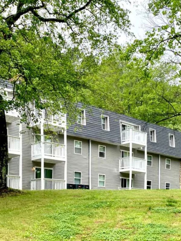 A grey apartment building with green trees in the background.