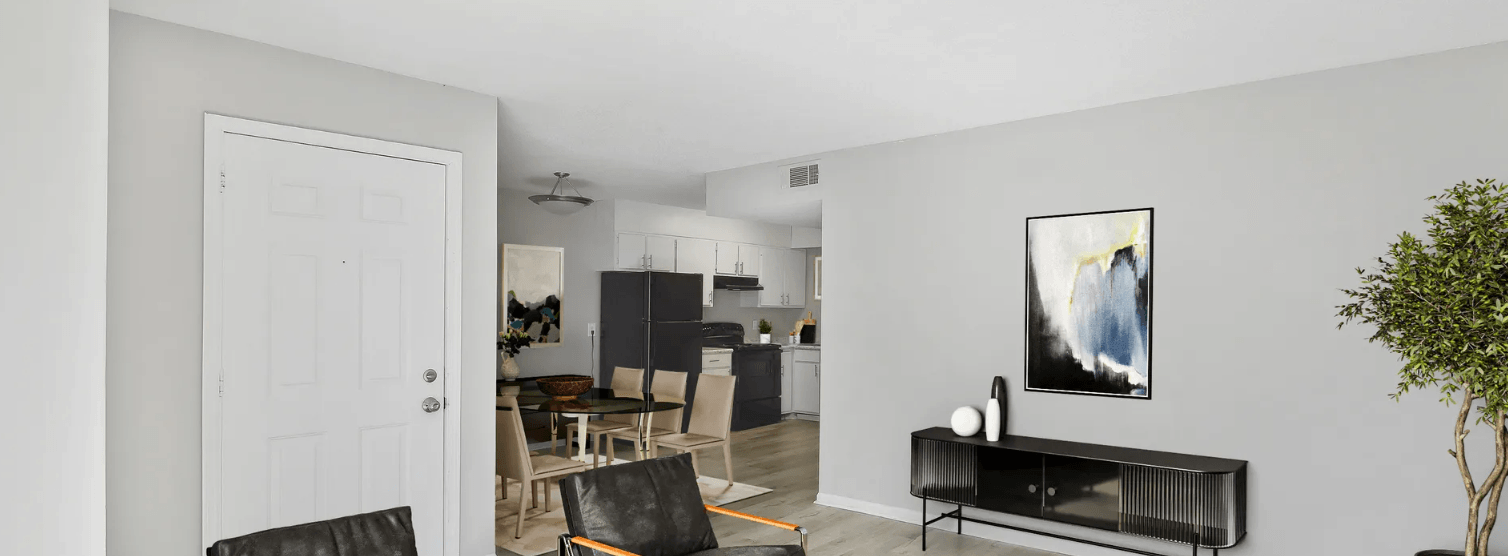 A living room with a black sofa and a painting on the wall.