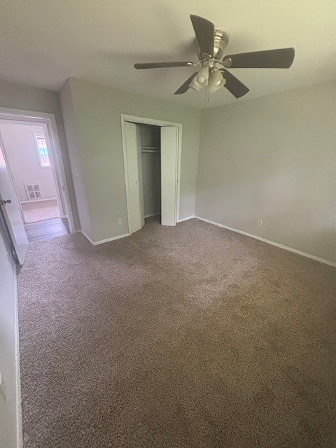 A room with a ceiling fan and carpeted floor.