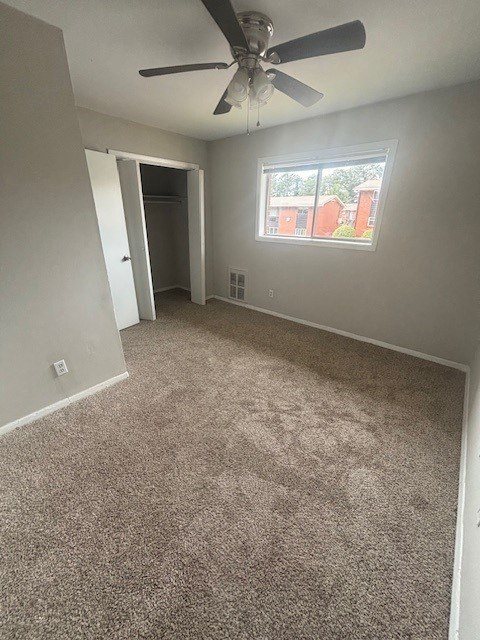 A room with a ceiling fan and carpeted floor.