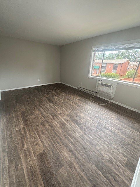 A room with wooden flooring and a window overlooking a red building.