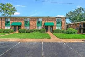 A building with green awnings and a parking lot in front.