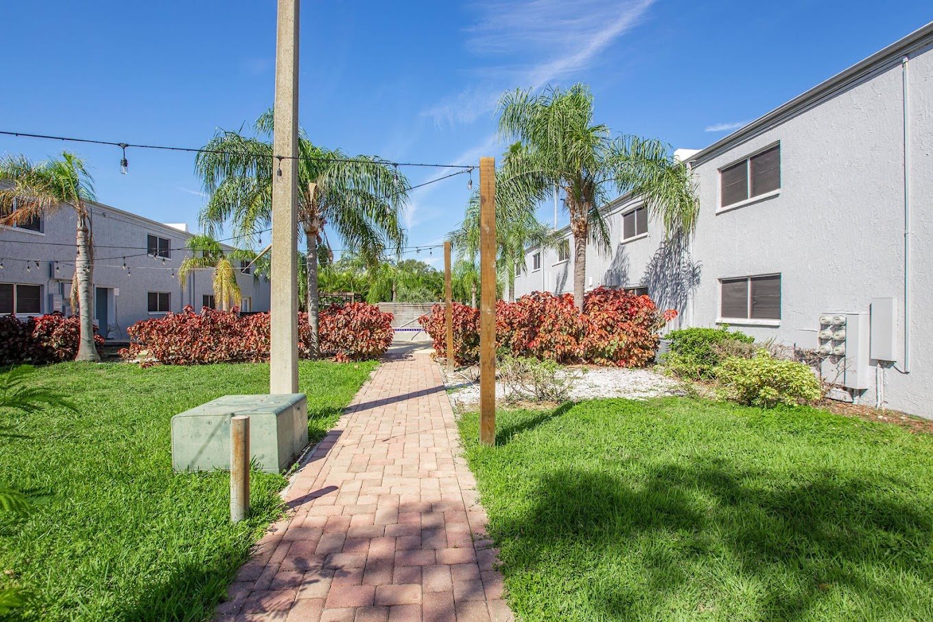 A pathway leads through a grassy area with a building on the right.