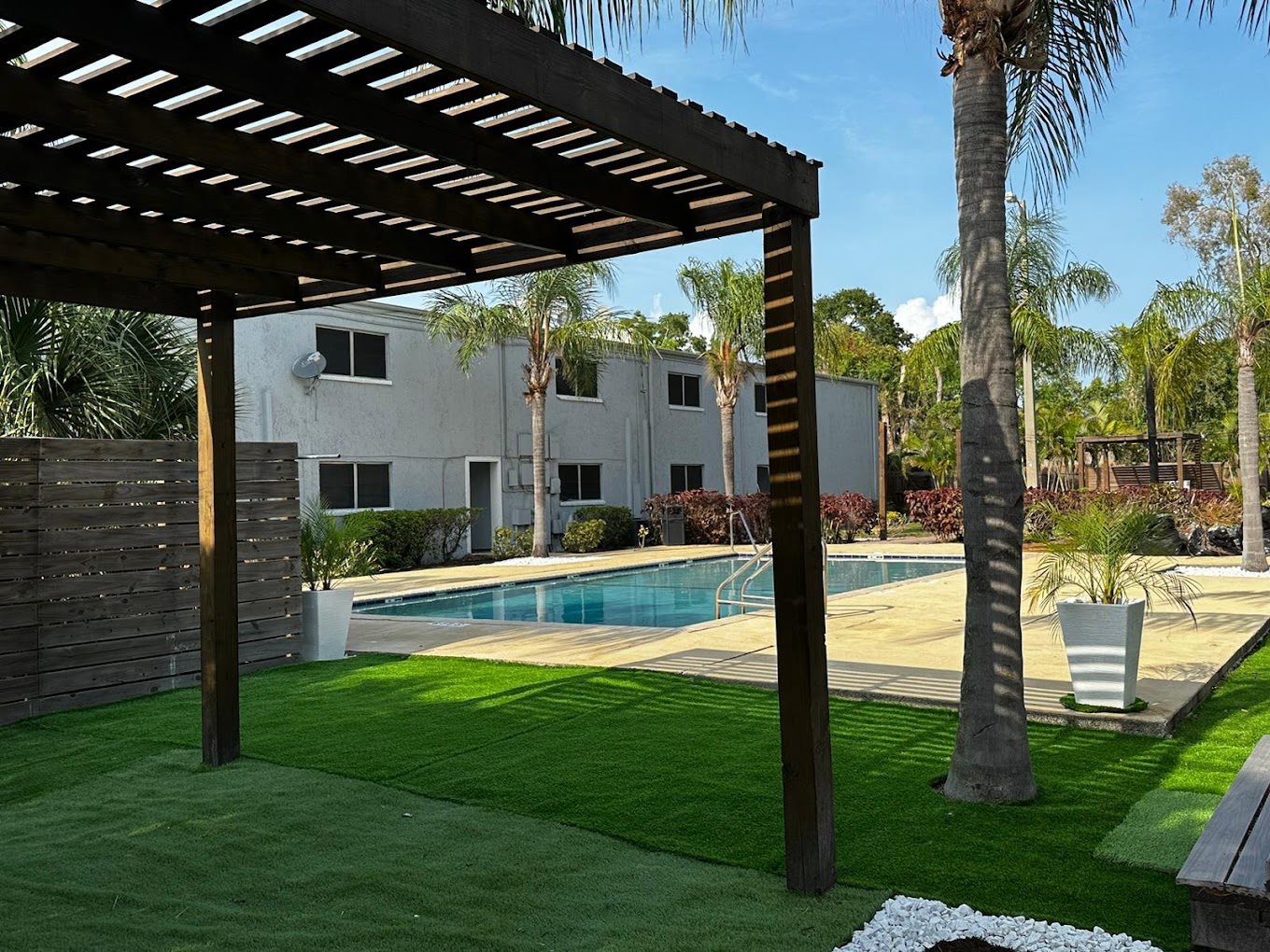A backyard with a pool and a wooden pergola.