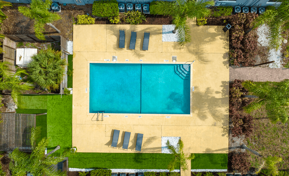An aerial view of a swimming pool surrounded by a grassy area and trees.