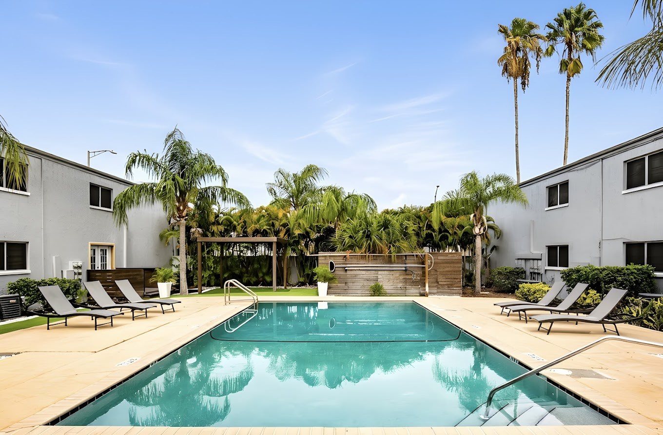 A swimming pool surrounded by palm trees and lounge chairs.