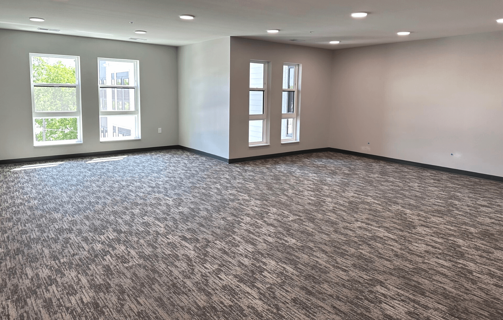 an empty room with three windows and a carpeted floor