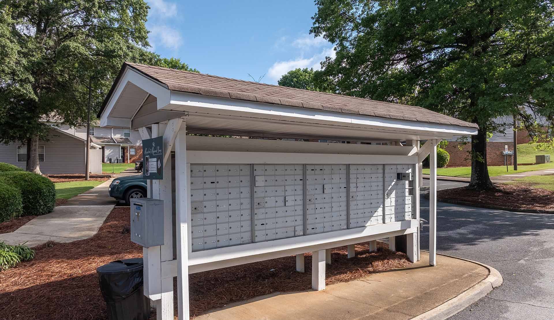 A white wooden bench with a white roof is in front of a building.