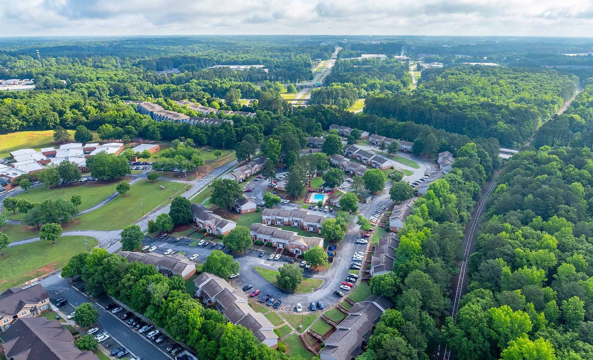 A bird's eye view of a residential area with houses, roads, and greenery.