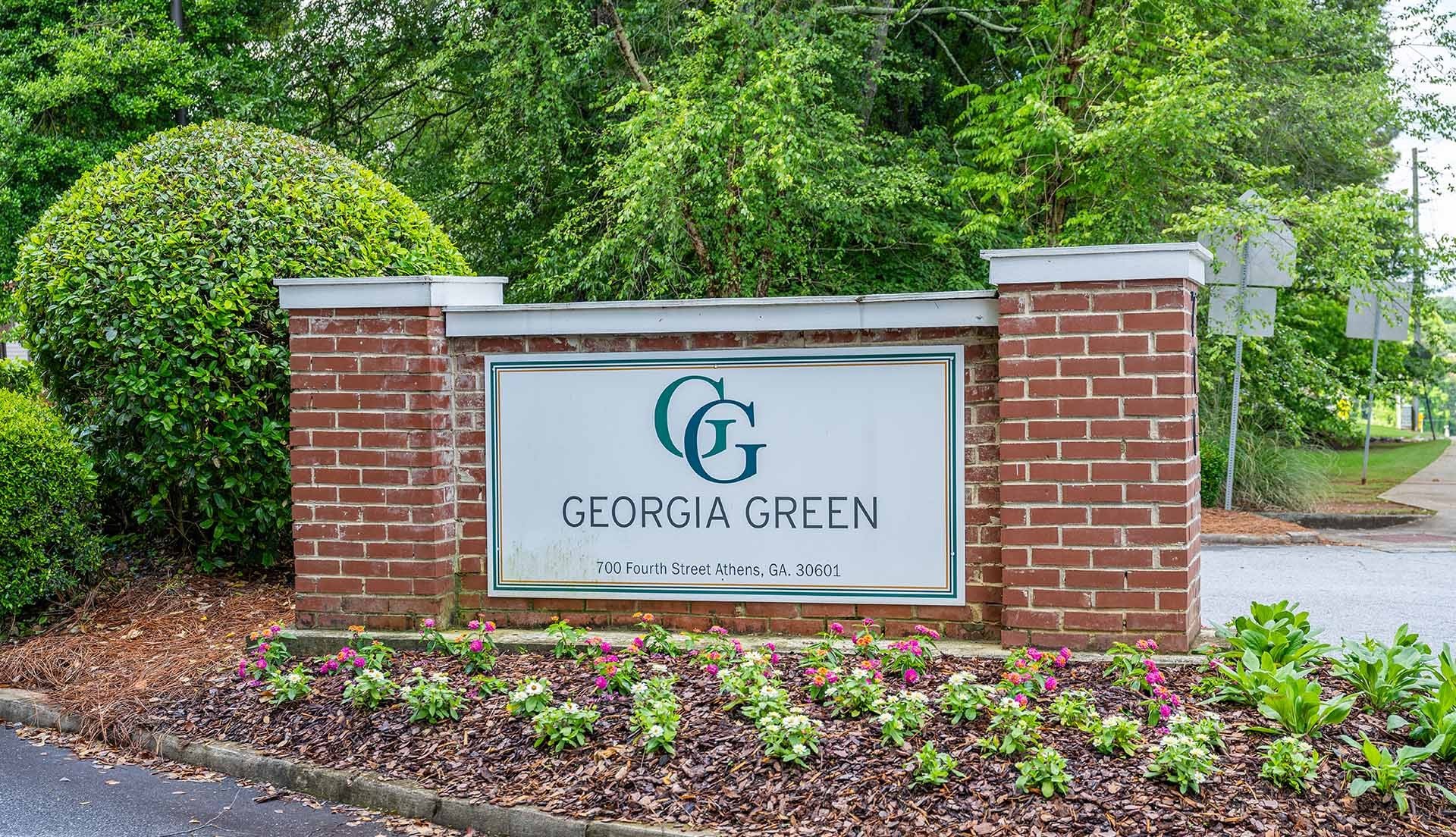 A sign for Georgia Green is displayed in front of a green hedge.