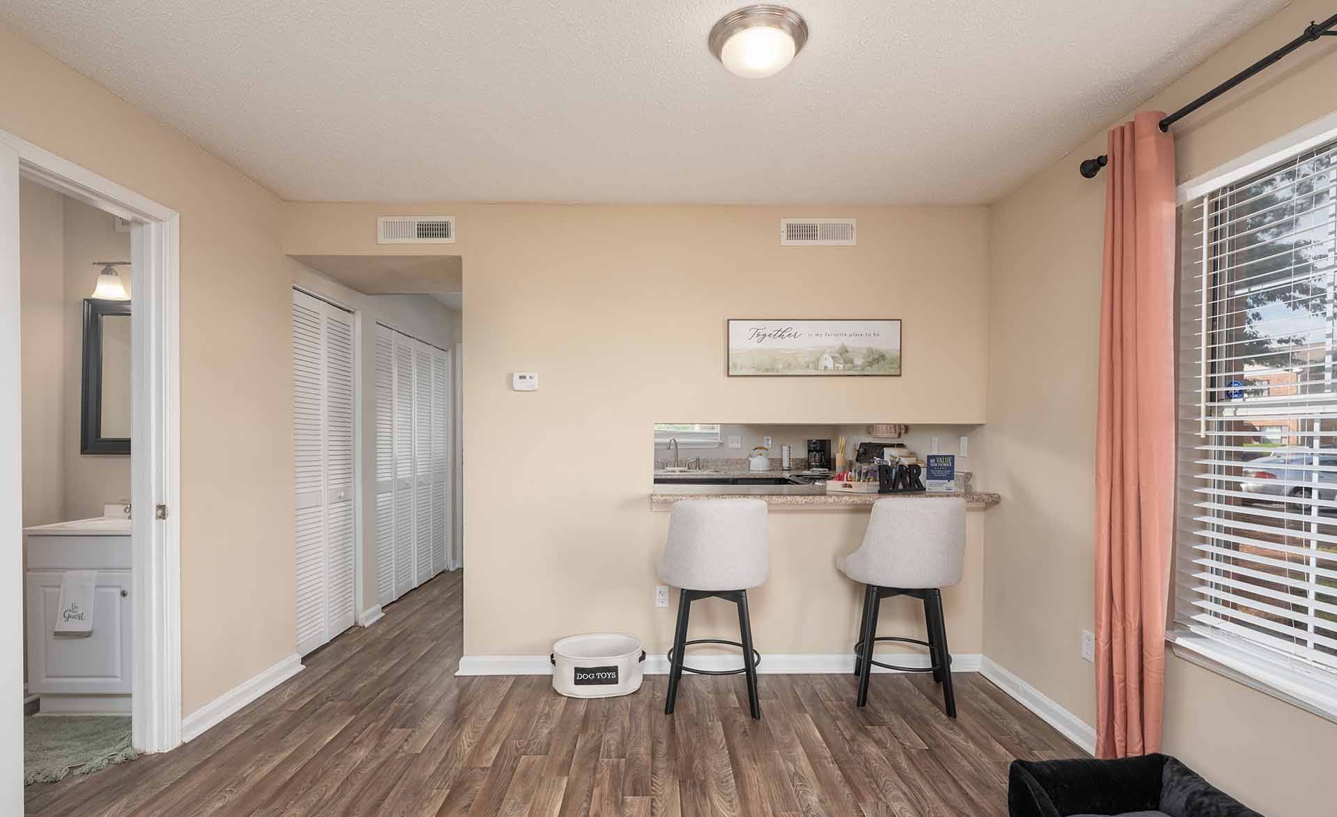 A kitchen with a bar stool and a fridge.