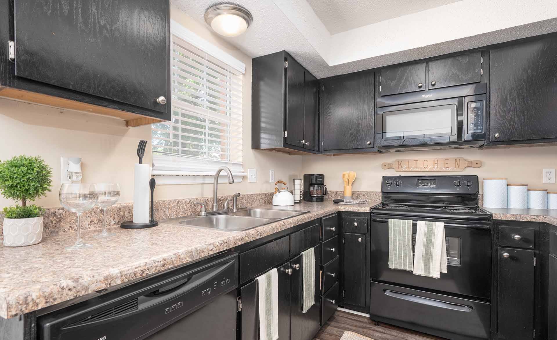 A black kitchen with granite countertops and a black oven.