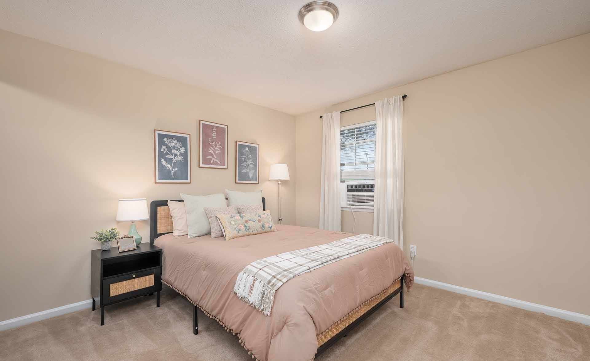 A bedroom with a bed, nightstand, and pictures on the wall.