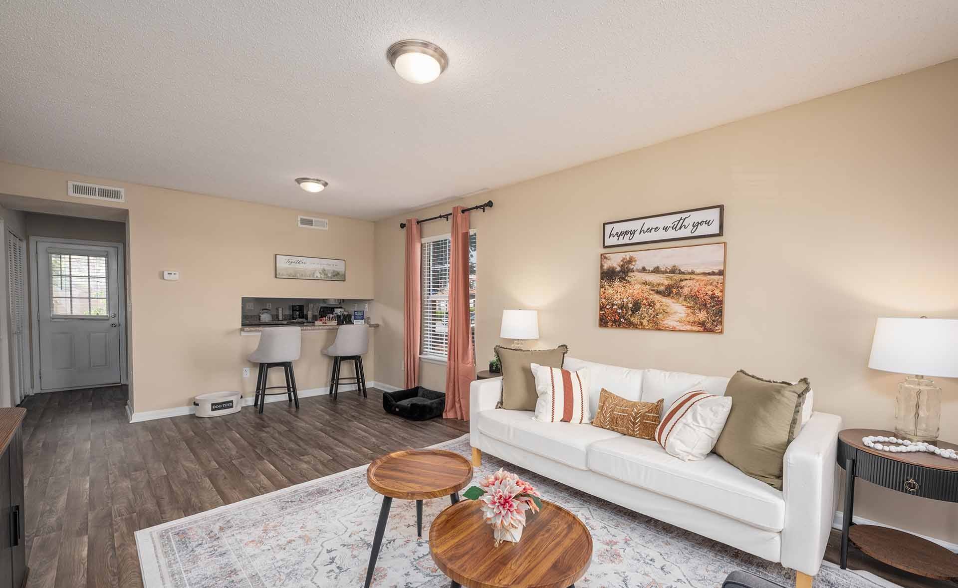 A living room with a white couch, a coffee table, and a painting on the wall.