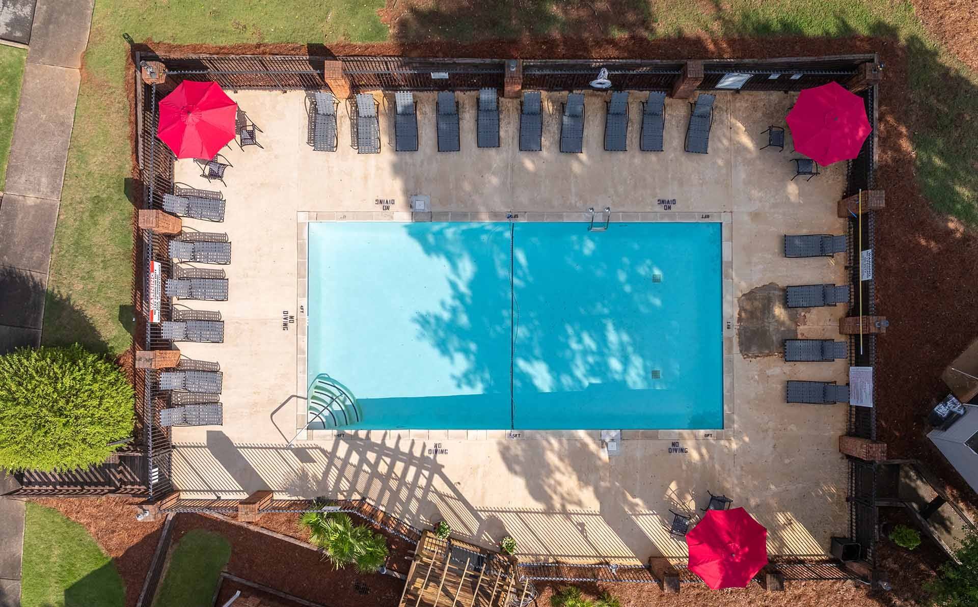 An aerial view of a pool surrounded by lounge chairs and umbrellas.