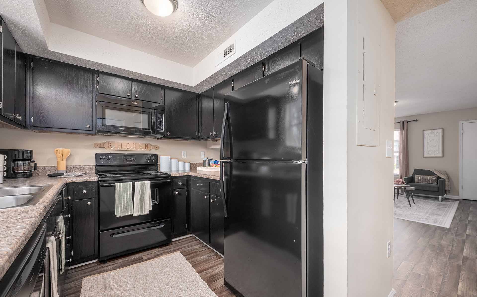 A black fridge in a kitchen with black cabinets.