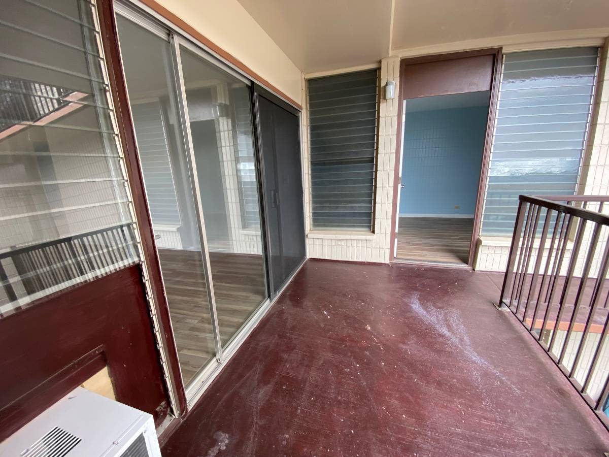 A balcony with a red floor and a white air conditioner unit.