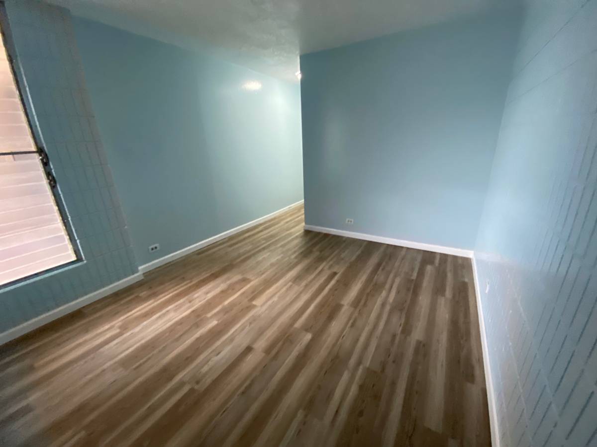 A room with wooden flooring and a window on the left side.