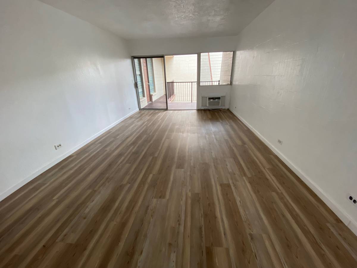 A room with wooden flooring and a balcony with a railing.