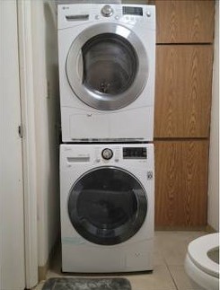 Two washing machines stacked on top of each other in a bathroom.
