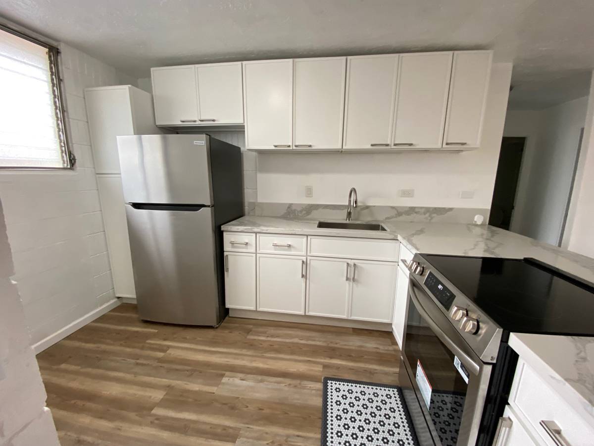 A kitchen with white cabinets and a black fridge.
