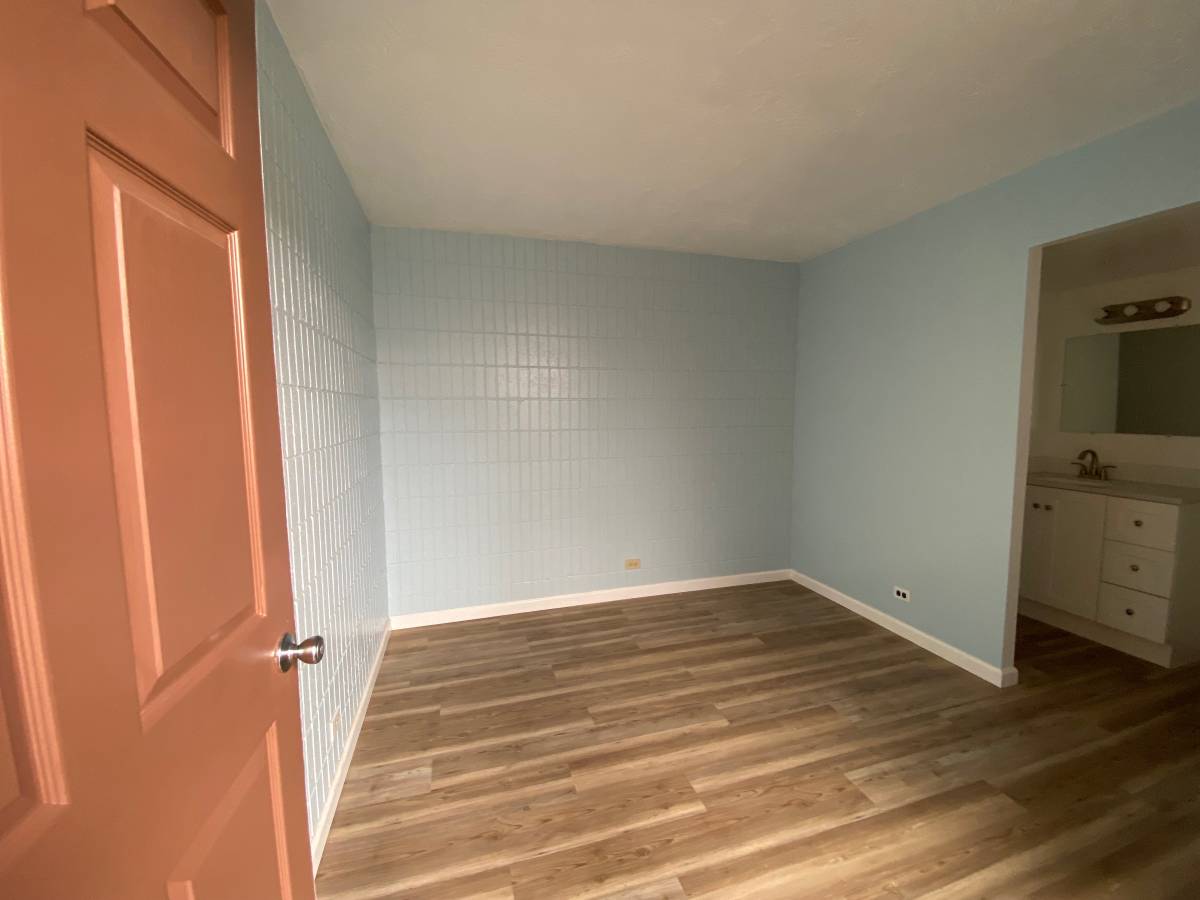 A room with wooden floors and a door on the left.