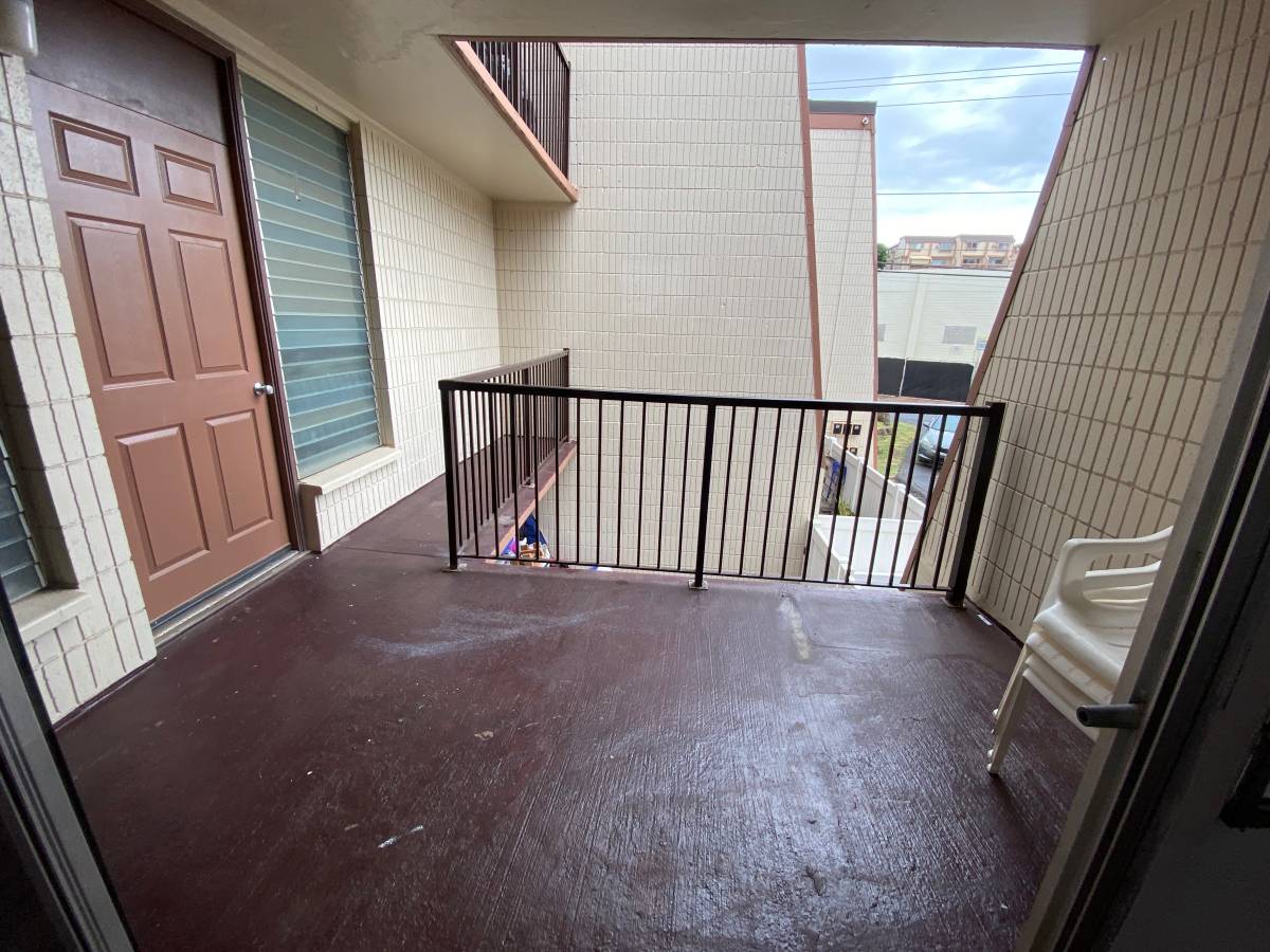 A balcony with a brown door and a black railing.