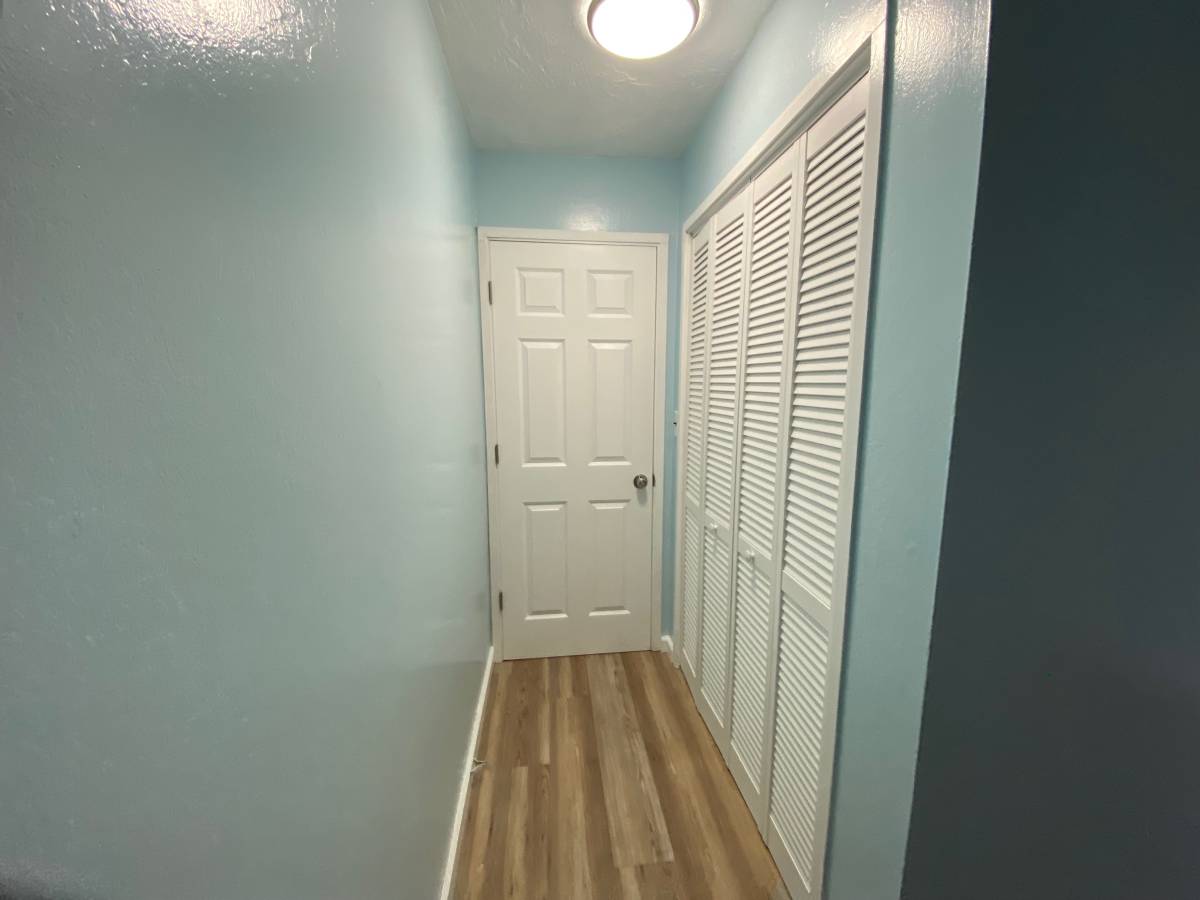 A white door is in the middle of a hallway with blue walls.