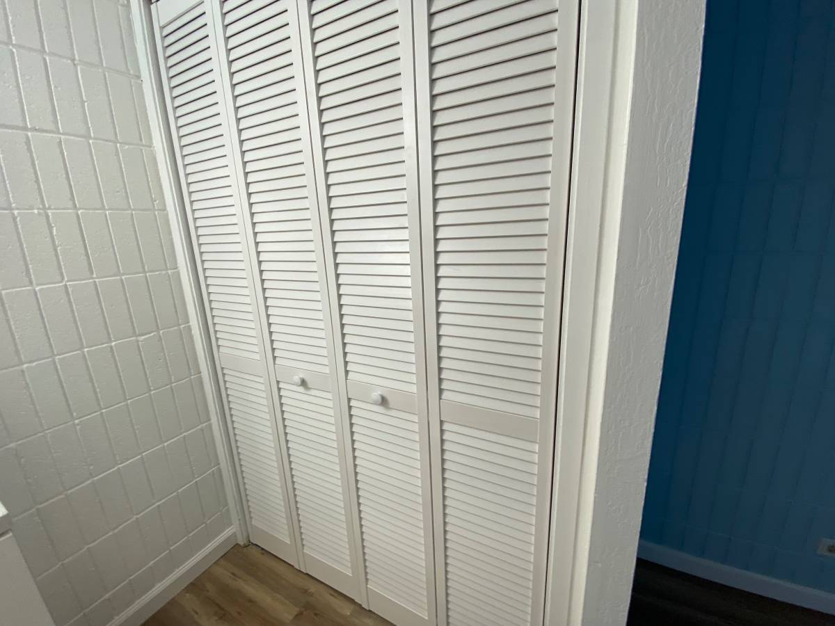 Closet with white doors and tiled wall.