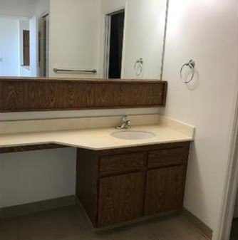 A bathroom sink with a brown cabinet and a mirror above it.