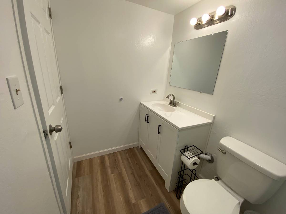 A white bathroom with a toilet, sink, and mirror.