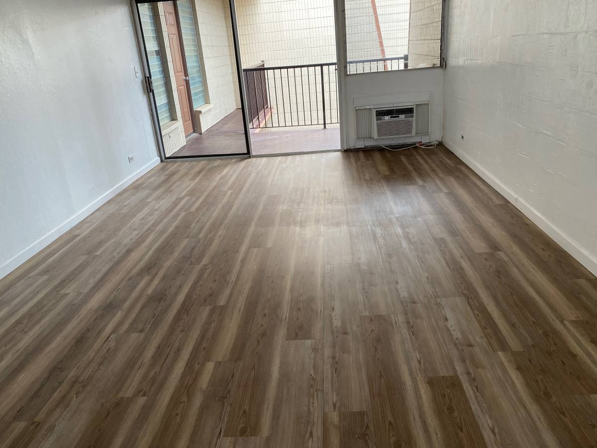 A room with wooden flooring and a balcony with a railing.