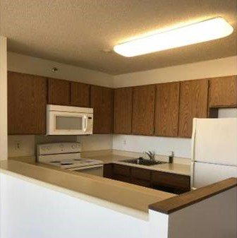 A kitchen with brown cabinets and white appliances.